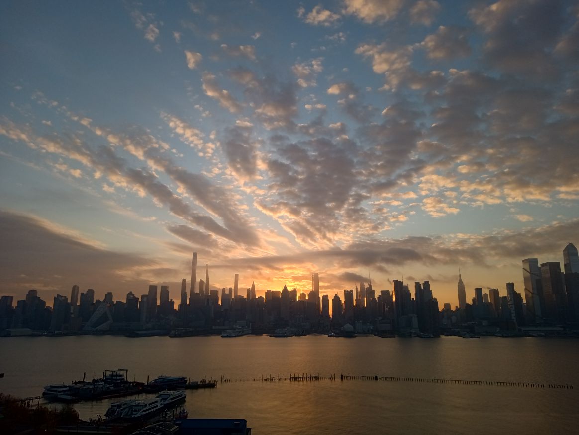 Sun rising behind NYC skyline